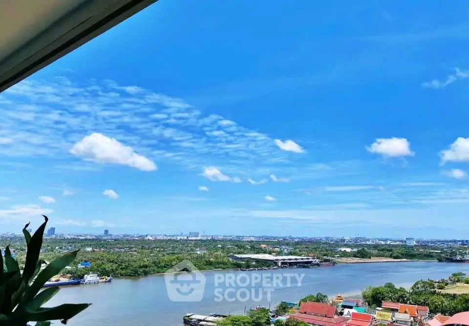 Stunning river view from high-rise apartment balcony with clear blue skies.