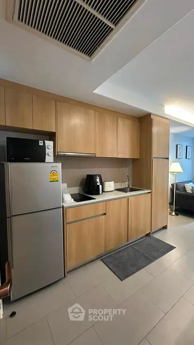 Modern kitchen with sleek wooden cabinets and stainless steel appliances in a stylish apartment.