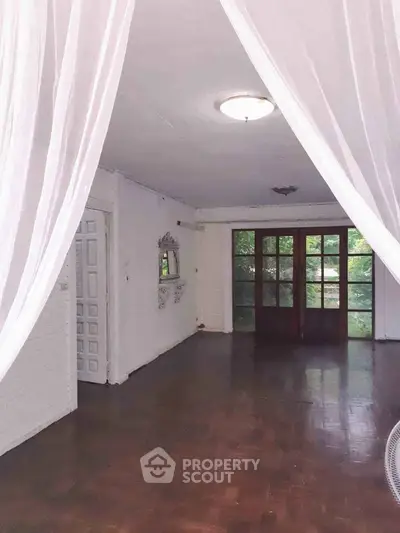 Spacious living room with elegant drapes and large windows overlooking greenery