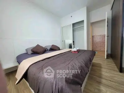 Modern bedroom with cozy bedding and wooden flooring, featuring a spacious closet.