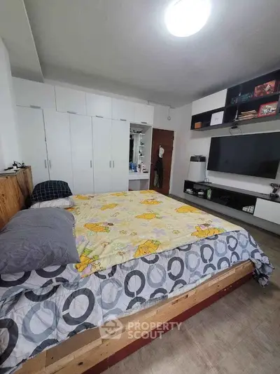 Spacious bedroom with large bed, ample built-in wardrobes, and modern entertainment unit, perfect for relaxation and storage needs.