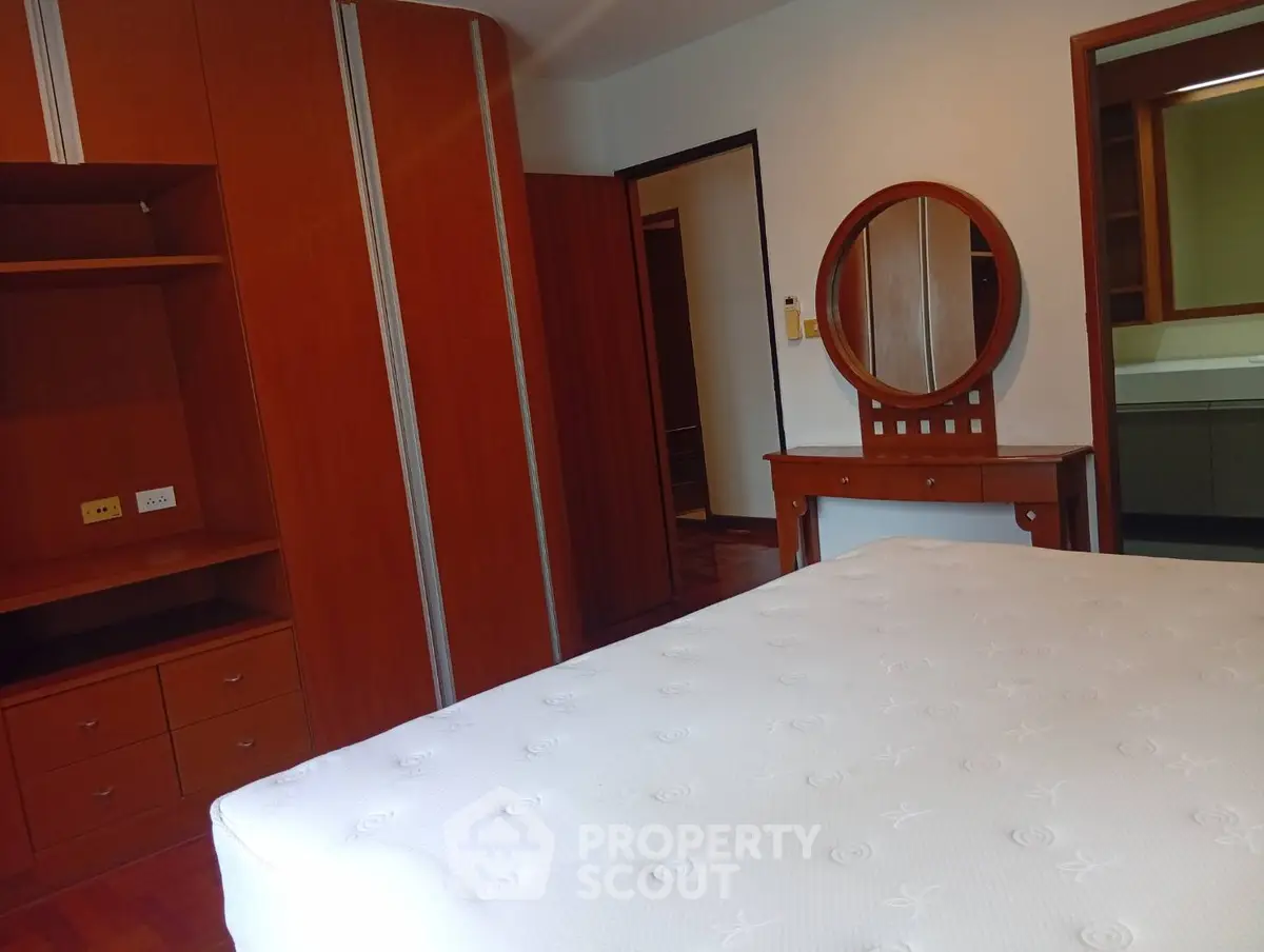 Spacious bedroom with elegant wooden furniture and a comfortable mattress, perfect for relaxation.