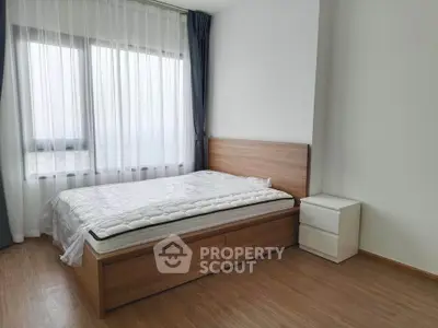Modern bedroom with wooden flooring and large window, featuring a minimalist bed and nightstand.