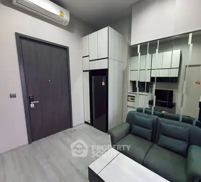 Modern apartment interior with sleek kitchen and cozy living area, featuring mirrored walls and contemporary furniture.