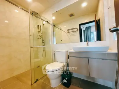 Modern bathroom with glass shower, sleek vanity, and elegant fixtures in a contemporary apartment.
