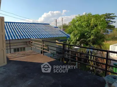 Charming balcony with scenic view of lush greenery and neighboring rooftops, perfect for relaxation.