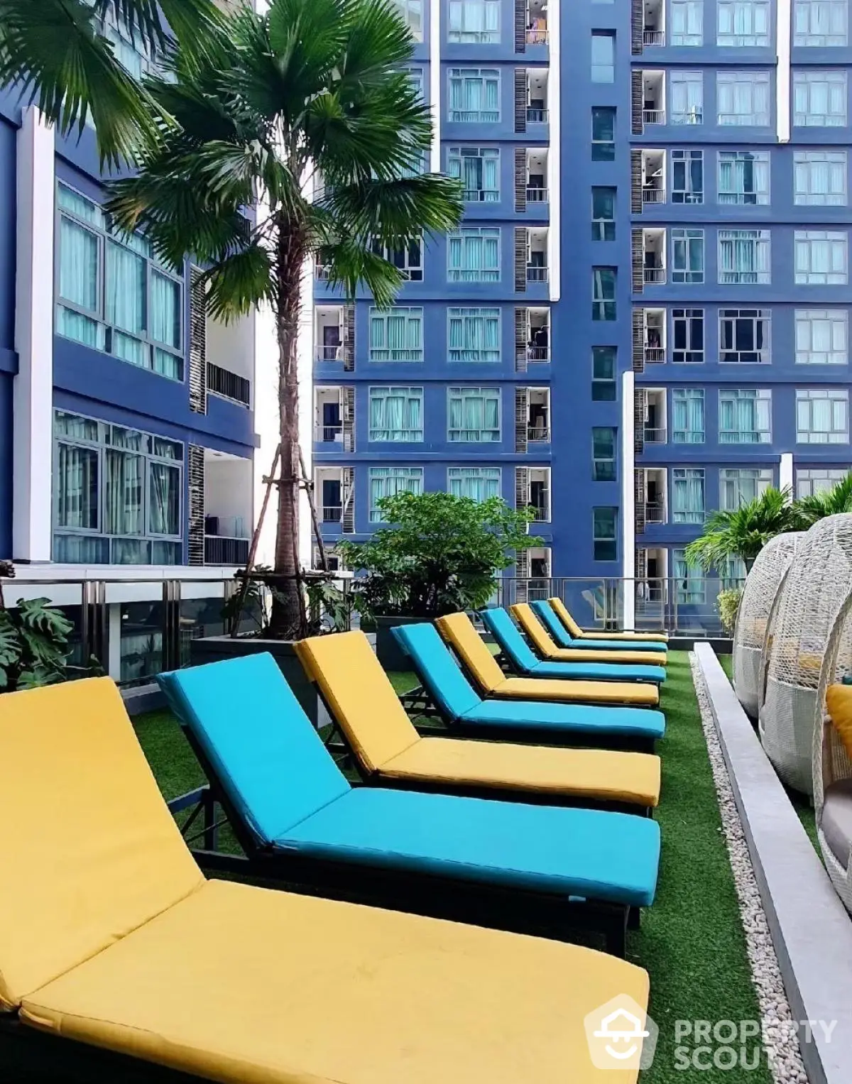 Luxurious apartment building with vibrant poolside lounge chairs and lush greenery