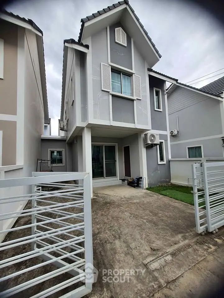 Modern two-story house with gray facade and gated driveway, perfect for family living.
