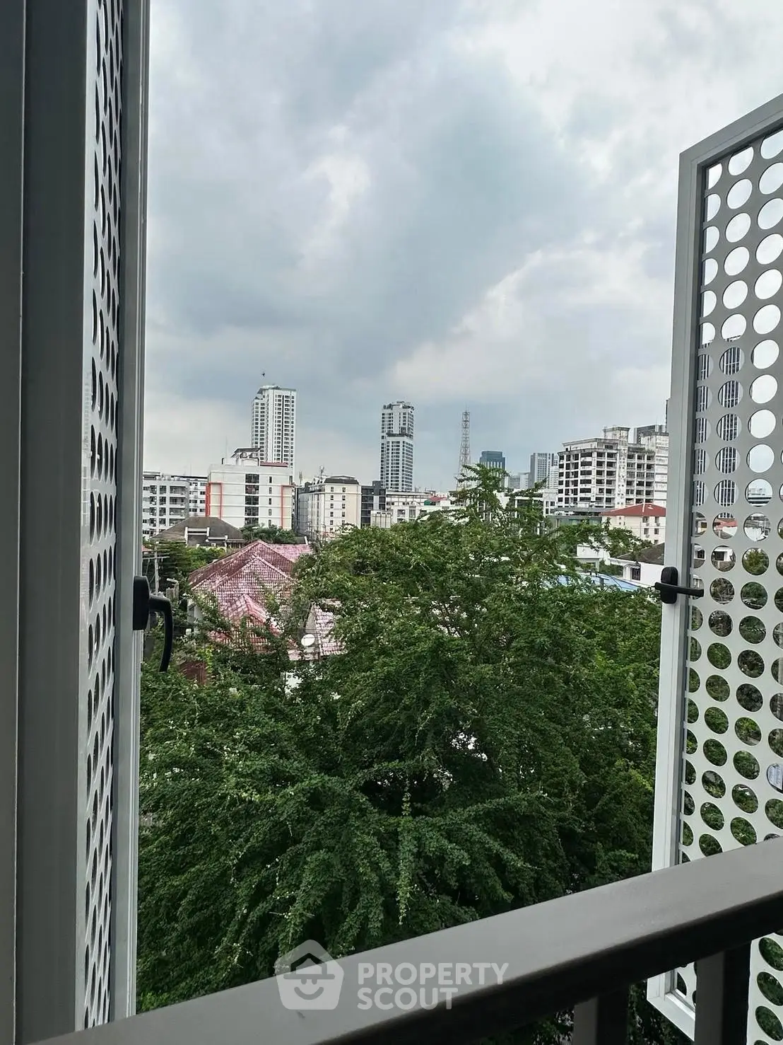 Stunning cityscape view from a modern balcony with lush greenery and urban skyline.