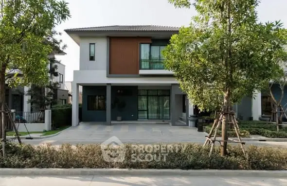 Modern two-story house with landscaped front yard and large windows in a suburban neighborhood.