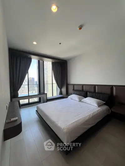 Spacious bedroom with large windows offering stunning city views
