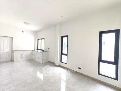 Spacious and bright living area with modern tiled flooring and large windows.