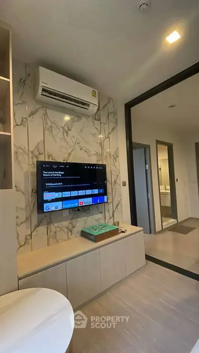 Modern living room with marble accent wall and mounted TV in stylish apartment.