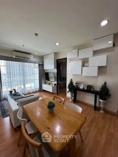 Modern living room with stylish decor and city view, featuring wooden flooring and contemporary furniture.