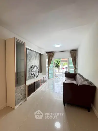 Spacious living room with modern decor and large windows opening to a balcony.