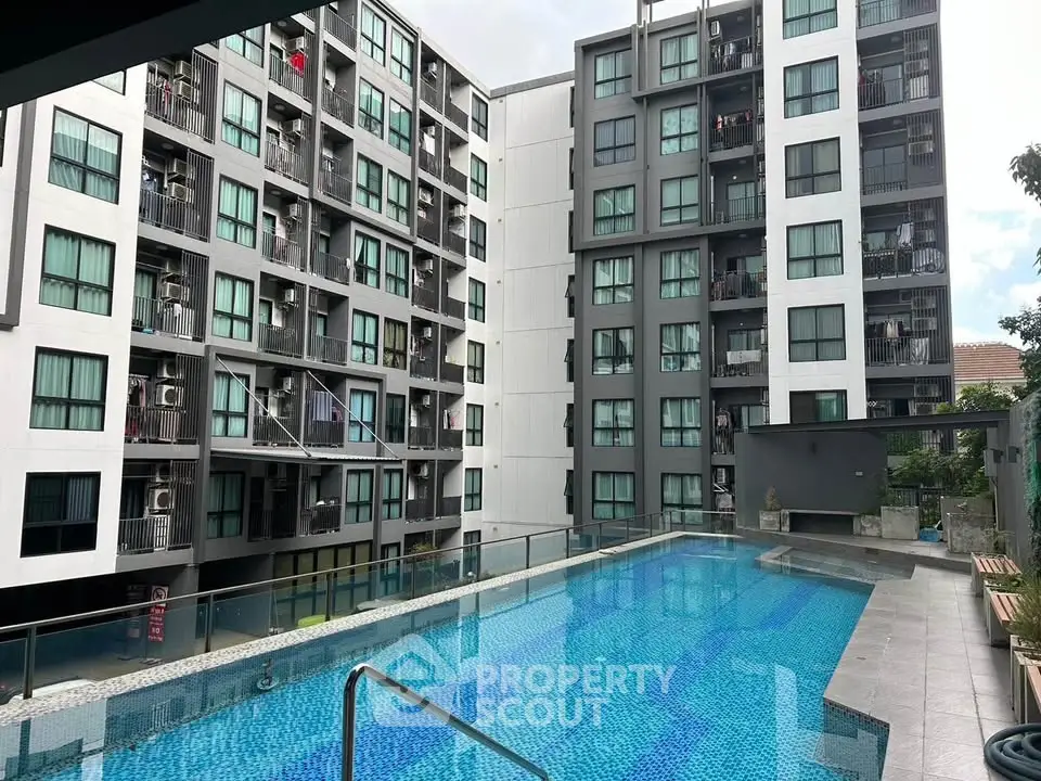 Modern apartment complex with a spacious swimming pool and sleek architecture.