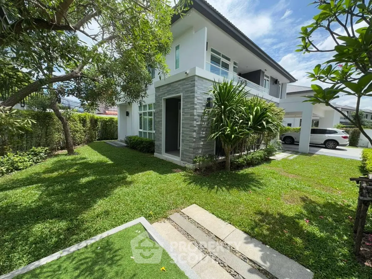 Charming two-story house with lush garden and driveway in a serene neighborhood.