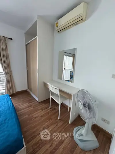 Cozy bedroom with wooden flooring, built-in wardrobe, and air conditioning, perfect for comfortable living.