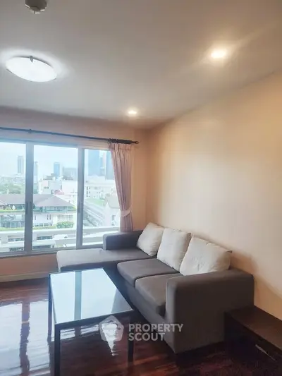 Spacious living room with city view, featuring a cozy sofa and large windows for natural light.