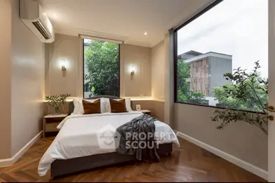 Luxurious bedroom with large window and modern decor offering serene garden views.