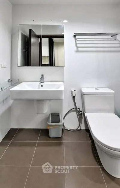 Modern bathroom with sleek fixtures and minimalist design, featuring a wall-mounted sink and toilet.