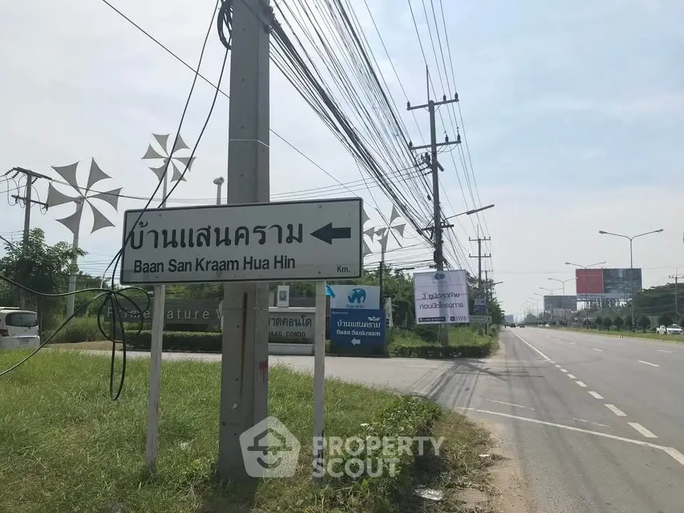Roadside sign pointing to Baan San Kraam Hua Hin with clear sky and power lines.