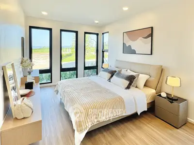 Modern bedroom with large windows and stylish decor, offering a serene view and cozy ambiance.