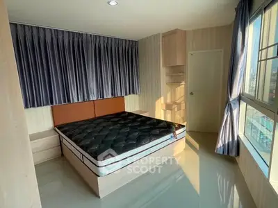 Spacious bedroom with large window and modern furnishings in a high-rise apartment.