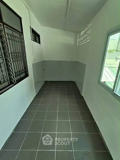 Spacious tiled balcony with windows and security bars, ideal for relaxation.