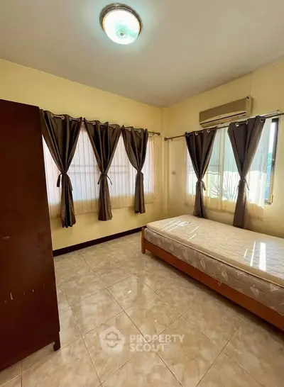 Spacious bedroom with natural light and tiled flooring, featuring a single bed and wardrobe.