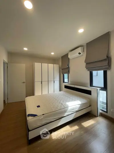 Spacious bedroom with modern furnishings and ample natural light, featuring a large bed and stylish wardrobe.