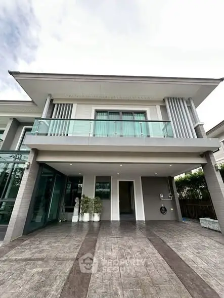 Modern two-story house with glass balcony and spacious driveway