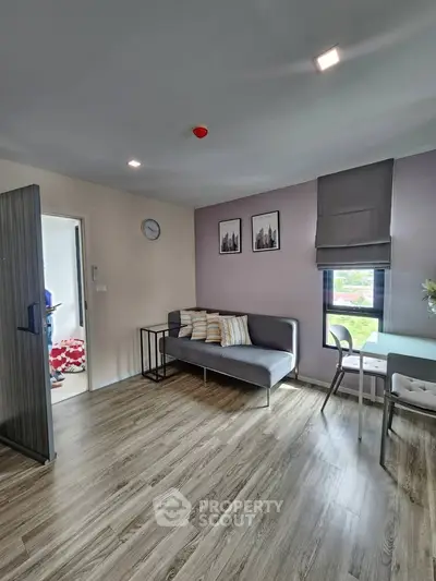 Modern living room with stylish decor and natural light, featuring a cozy sofa and dining area.