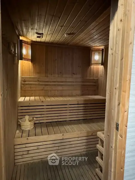 Luxurious wooden sauna room with warm lighting and tiered seating, perfect for relaxation.