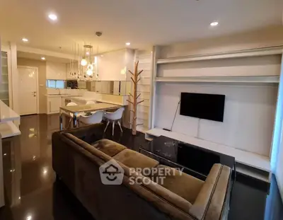 Modern open-layout living room with sleek kitchen, stylish lighting, and contemporary furniture.