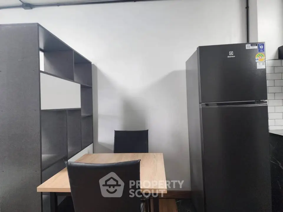 Modern kitchen with sleek black fridge and dining area, perfect for contemporary living.