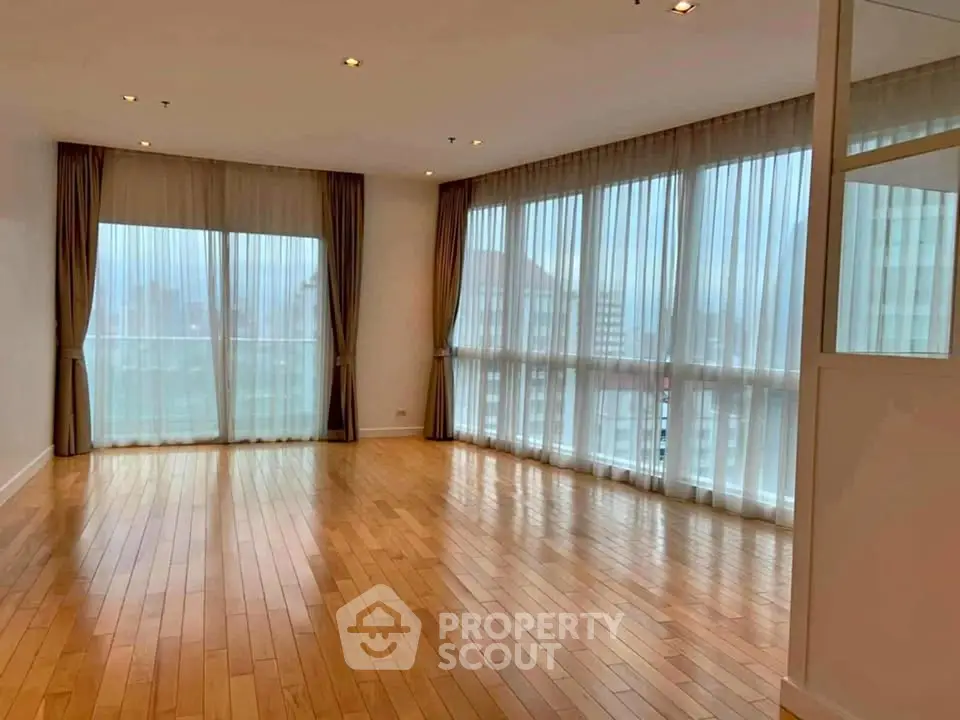 Spacious corner unit with large windows and hardwood floors in a modern apartment.