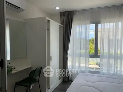 Bright bedroom with large window, modern wardrobe, and air conditioning.