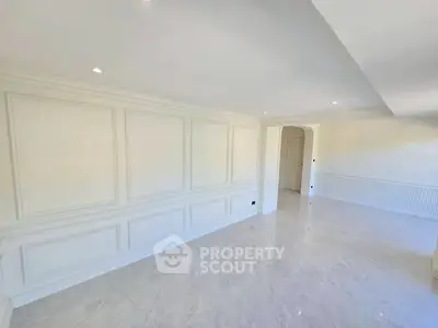 Spacious and elegant living room with marble flooring and classic wall paneling