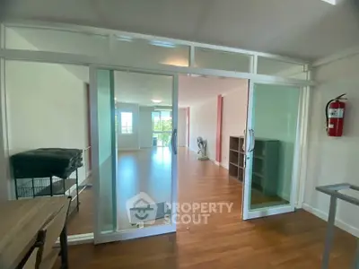 Spacious living room with wooden flooring and glass sliding doors in modern apartment.