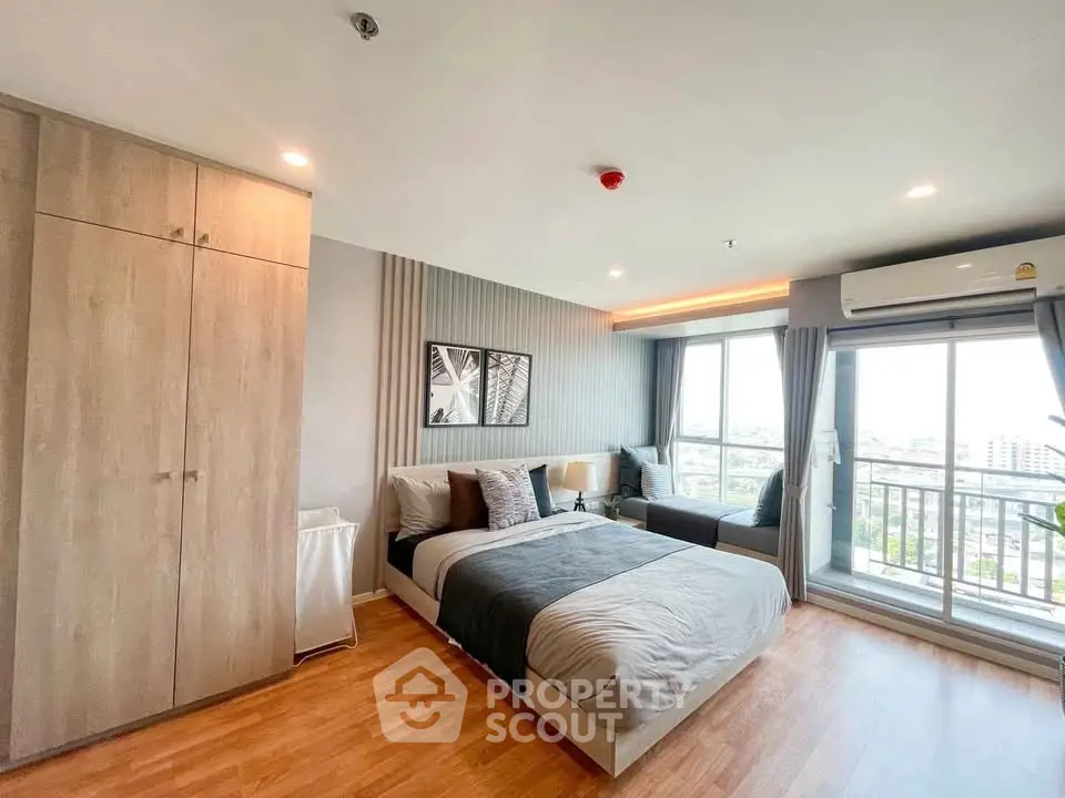 Modern bedroom with large windows and city view, featuring stylish decor and ample natural light.