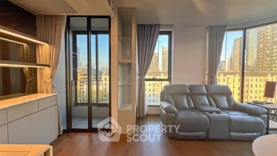 Modern living room with large windows and city view, featuring a cozy leather sofa and elegant decor.