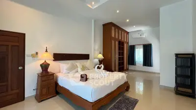 Spacious bedroom with elegant wooden furniture and modern decor in a luxury home.