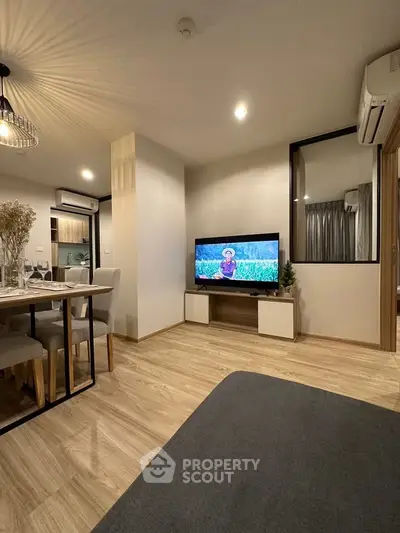 Modern living room with stylish decor and open dining area, featuring a mounted TV and elegant lighting.