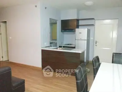 Modern open-layout kitchen with sleek cabinetry and dining area in a cozy apartment.