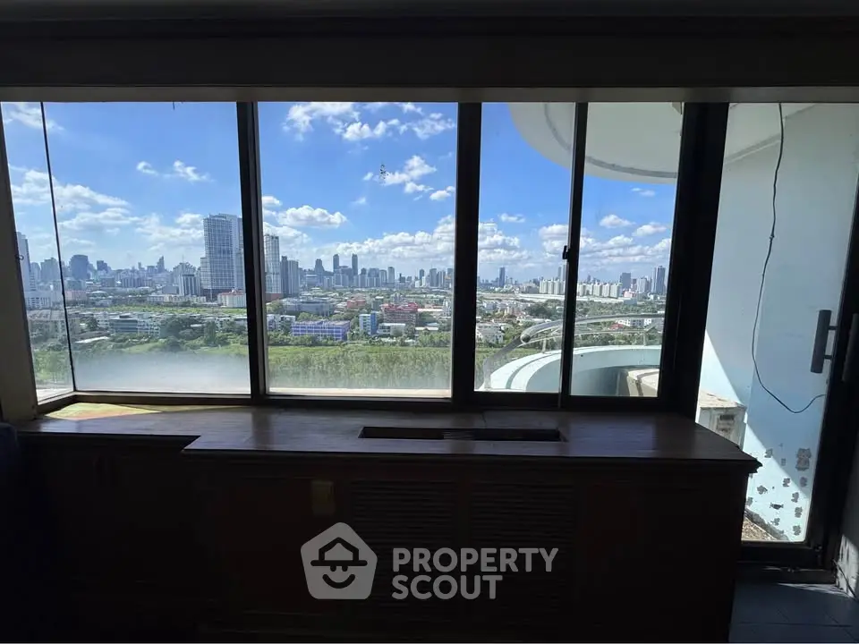 Stunning cityscape view from a high-rise apartment window, showcasing urban skyline and blue skies.