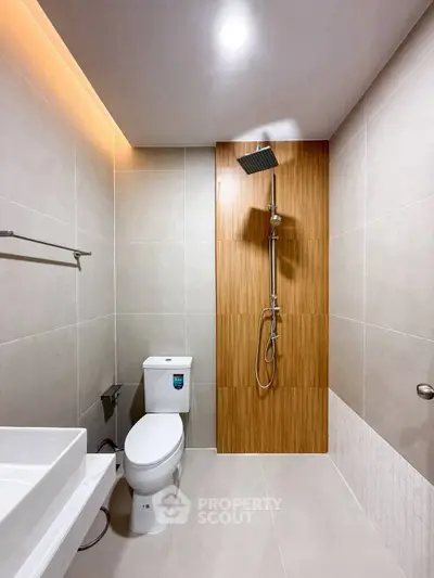 Modern bathroom with sleek design, featuring a rainfall shower and contemporary fixtures.
