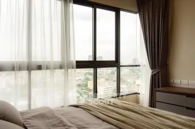 Spacious bedroom with large windows offering a stunning city view.