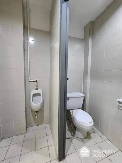 Compact and functional bathroom with ceramic tiles, featuring a toilet and a separate urinal, ideal for efficient use in a busy household or commercial space.