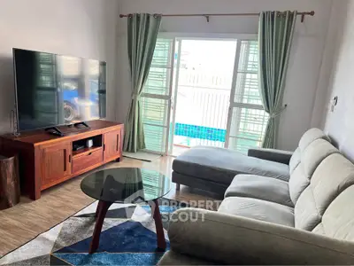 Spacious living room with modern furniture and pool view, perfect for relaxation and entertainment.